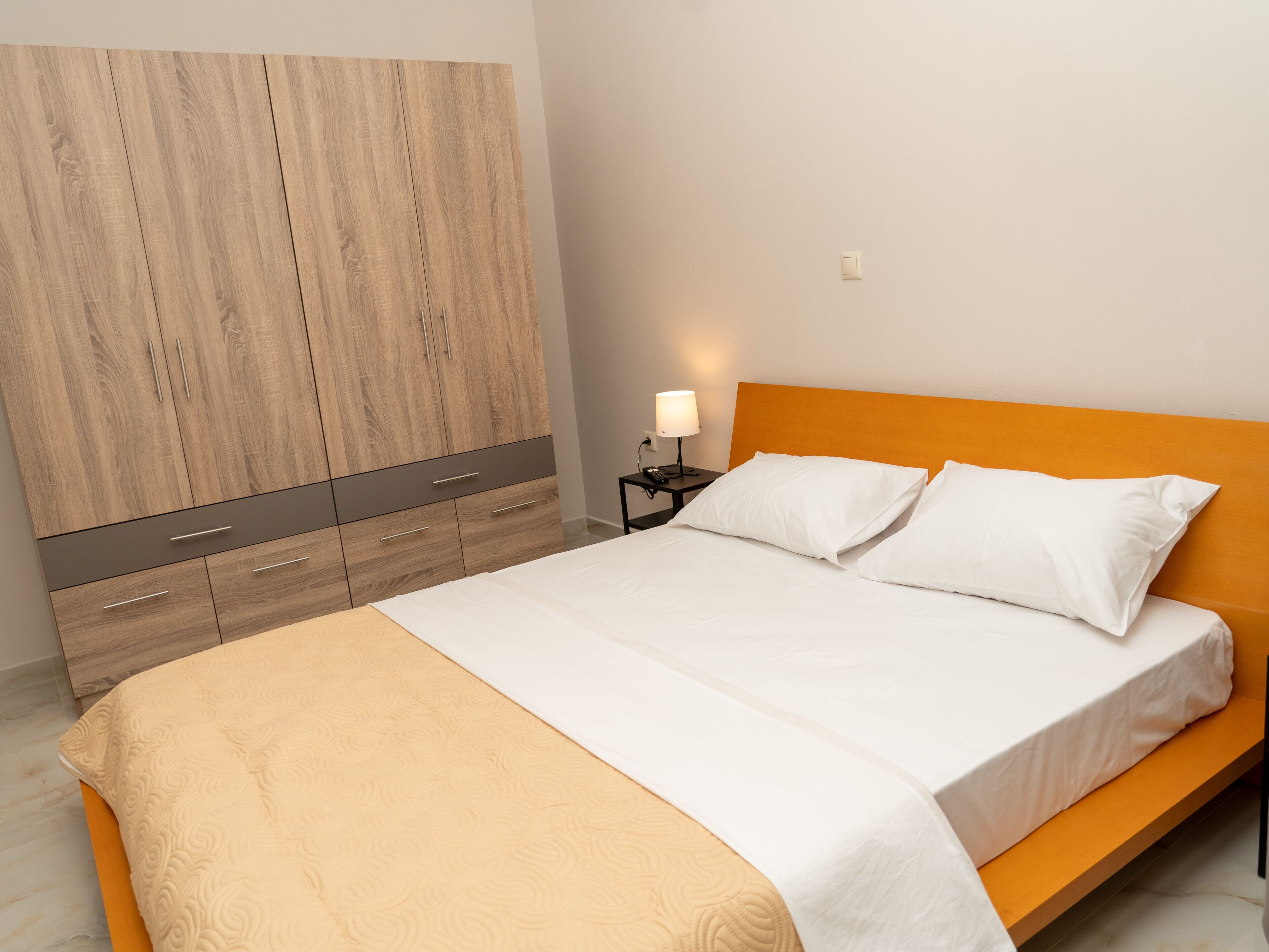 Un dormitorio con una cama, una mesita de noche, una lámpara y un armario.