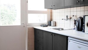 A kitchen with dark cabinets, a white countertop, a sink, and a refrigerator. - Best Located Executive Apartment in Maroussi
 (Marousi)