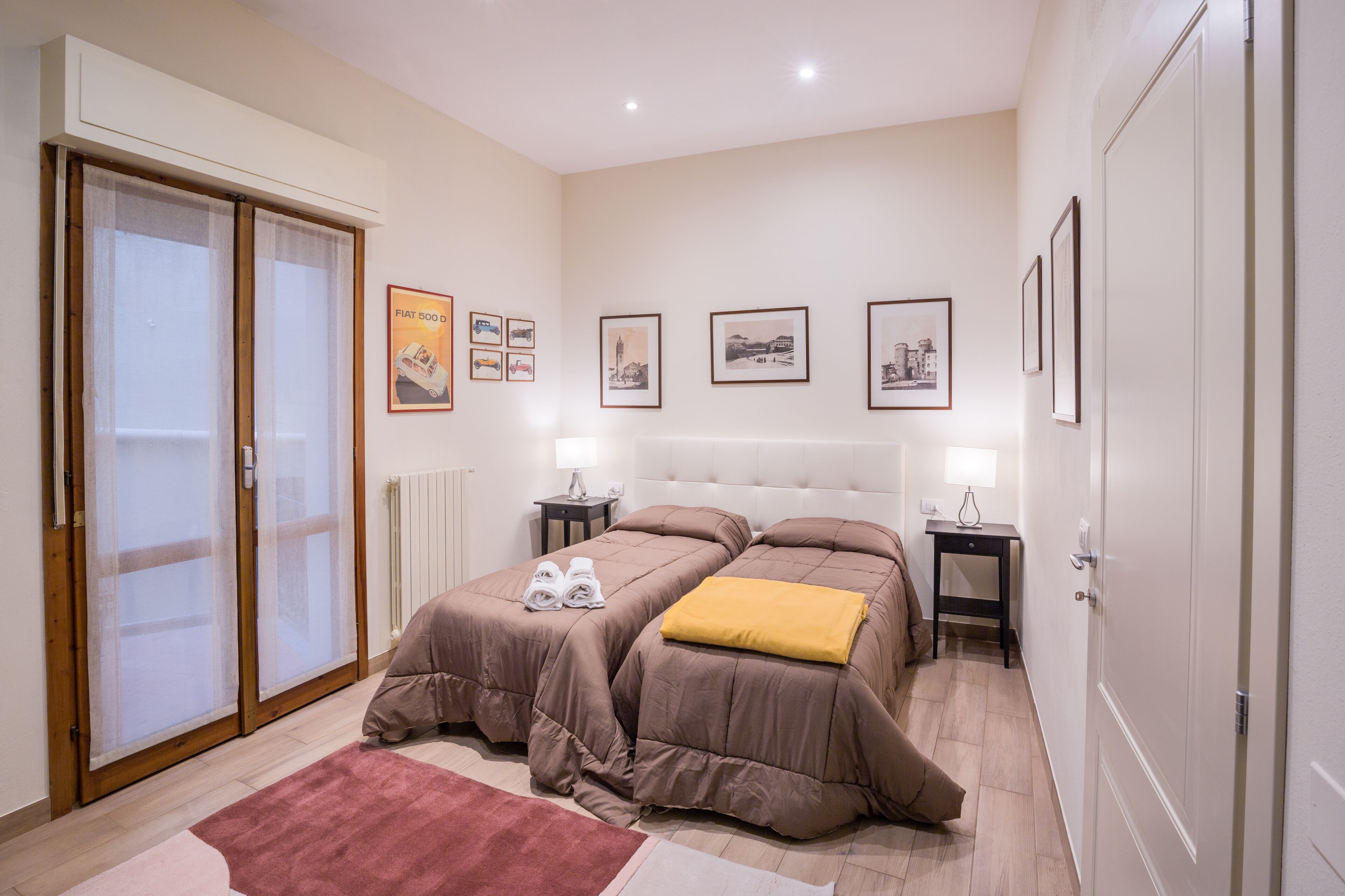 Ein Schlafzimmer mit zwei Betten, einer Schiebetür und gerahmten Bildern an der Wand.