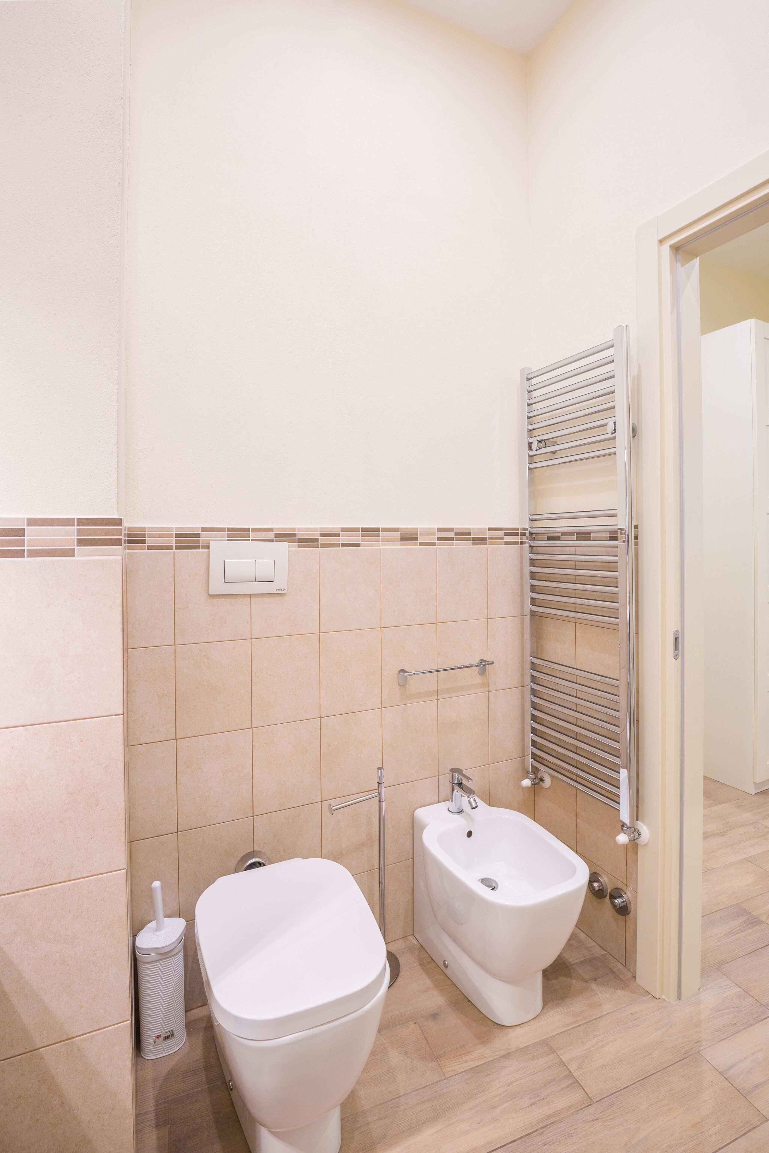 Een badkamer met toilet, bidet en een handdoekrek.