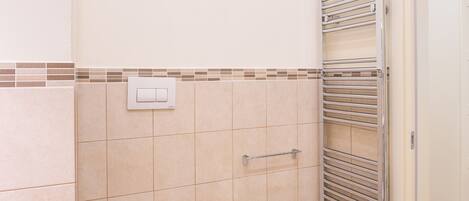 A bathroom with a toilet, bidet, and a towel rack.