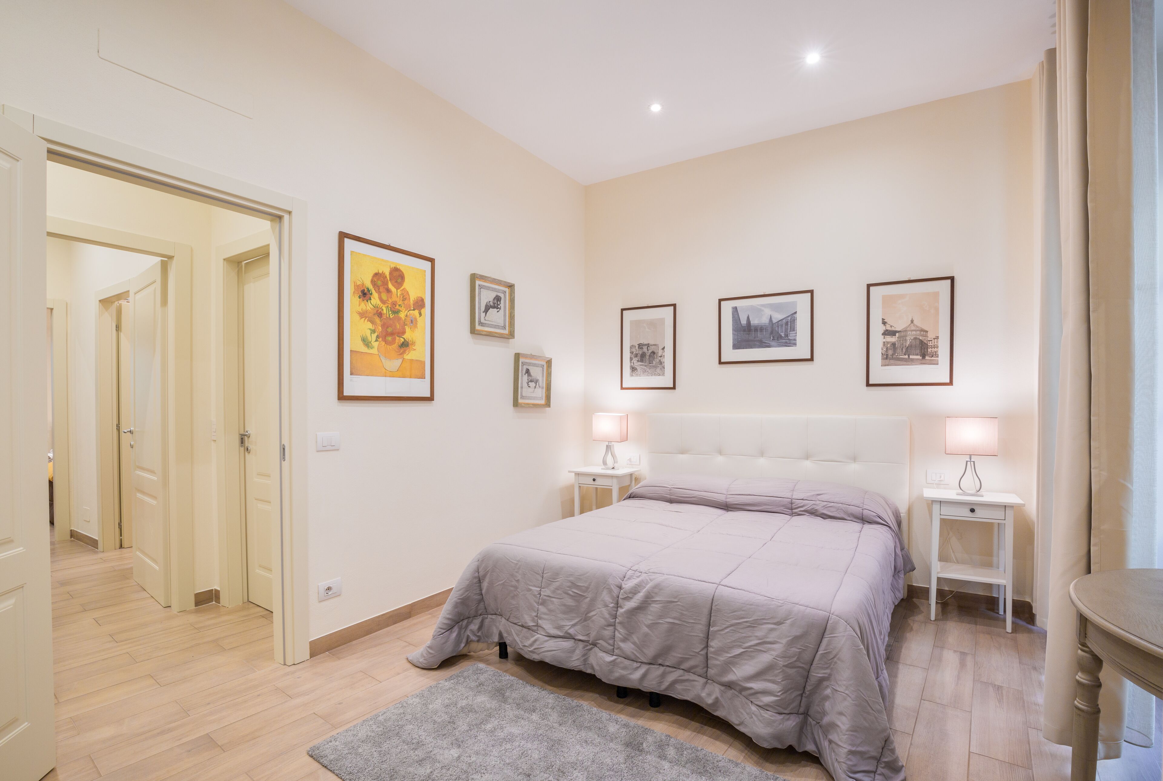 A bedroom with a bed, bedside tables, and wall-mounted artwork.