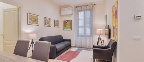 Ein modernes Wohnzimmer mit einem grauen Sofa, einem Holzesstisch und einem an der Wand montierten Fernseher.