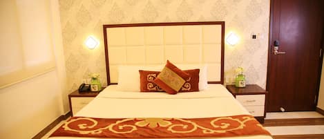 A neatly made bed with a headboard, two bedside tables with lamps, and a wooden door.