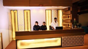 A reception desk with a modern design, featuring a wooden finish and a patterned backdrop.