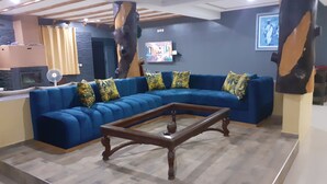 Una sala de estar con un sofá seccional azul, una mesa de centro de madera y una chimenea de piedra.