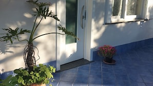 Ein Haus mit einer gepflasterten Terrasse, einer Tür und einem Fenster.