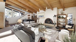 A spacious living room with a high wooden ceiling, a fireplace, a sofa set, and a bookshelf. - Ski-In/Ski-Out Snowmass Estate with Hot Tub, Fireplaces & Expansive Mountain Views (Snowmass Village)