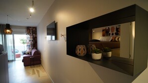 A modern interior with a sofa, a flat-screen TV, and a wall-mounted shelf with decorative items. - The Pearl of Bari (Bari)