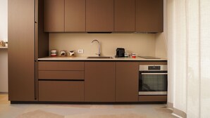 A modern kitchen with brown cabinetry, a stainless steel sink, and a built-in oven. - The Pearl of Bari (Bari)