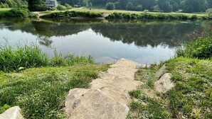 Un sendero que lleva a una masa de agua con una casa al fondo.