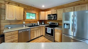 Una cocina moderna con armarios de madera, electrodomésticos de acero inoxidable y encimera de granito.