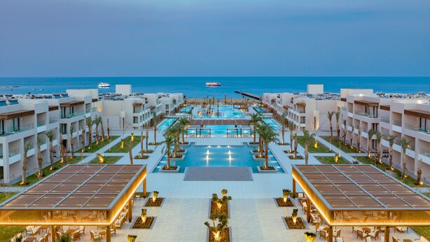 Un complexe hôtelier doté de plusieurs piscines, de palmiers et offrant une vue sur la mer.