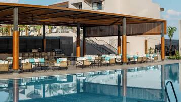A poolside area with outdoor seating, a covered section, and a staircase leading to an upper level.