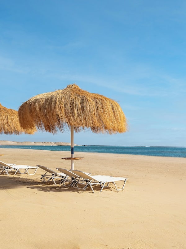 En la playa, sillas reclinables de playa, sombrillas, toallas de playa