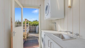 Una cucina compatta con lavatrice integrata, un lavandino e un patio in legno che dà sull'esterno.