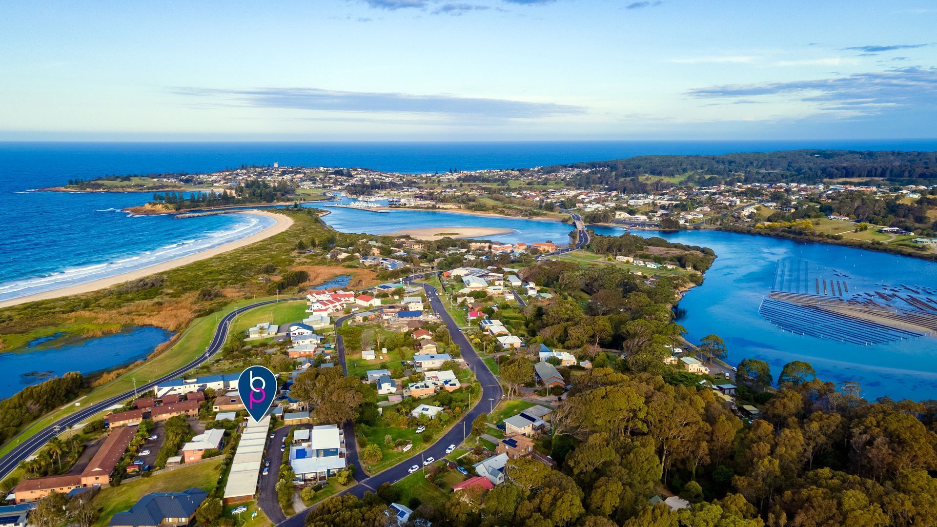An aerial view of a coastal town with residential areas, a marina, and a large body of water.