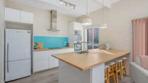 Una cucina moderna con mobili bianchi, un piano di lavoro in legno, un forno integrato e una finestra con vista.
