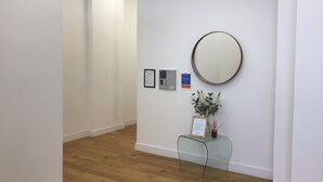 A hallway with wooden flooring, white walls, and a glass bench with a framed certificate. - Central Teignmouth - Sleeps 4 - Pets Allowed (Teignmouth)