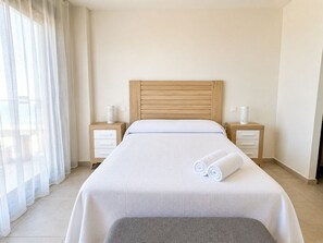 Une chambre d’hôtel avec un lit, deux tables de chevet, une fenêtre avec des rideaux légers et une vue sur l’extérieur.