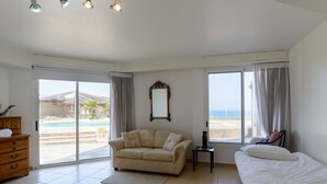 A room with a sofa, a bed, a small table, a mirror, and large windows with curtains. - MAMAD Coastal Mansion Private Pool in Netanya by FeelHome (Netanya)