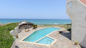 A swimming pool with a view of the ocean, a covered seating area, and a brick building. - MAMAD Coastal Mansion Private Pool in Netanya by FeelHome (Netanya)