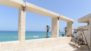 A balcony with a view of the ocean, a swing set, and a stone structure. - MAMAD Coastal Mansion Private Pool in Netanya by FeelHome (Netanya)