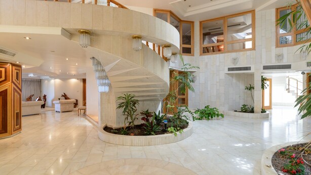 A spacious interior with a grand staircase, multiple seating areas, and indoor plants. - MAMAD Coastal Mansion Private Pool in Netanya by FeelHome (Netanya)