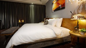 A hotel room with a large bed, a bench, a nightstand with a lamp, and a painting on the wall. - Hanoi Calido Hotel (Hanoi)