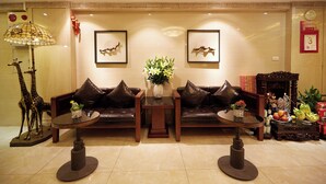 A lobby with a sofa set, a table with a vase, and a decorative giraffe sculpture. - Hanoi Calido Hotel (Hanoi)