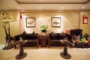 A lobby with a sofa set, a table with a vase, and a decorative giraffe sculpture. - Hanoi Calido Hotel (Hanoi)