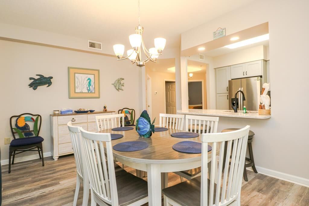 A dining area with a round table, white chairs, and a chandelier.