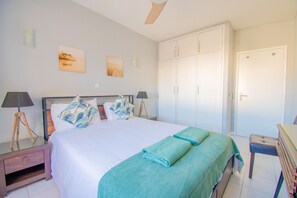 A bedroom with a bed, two bedside lamps, a nightstand, a desk, and a wardrobe. - 99B Hibiscus Monte Dourado (Carvoeiro)