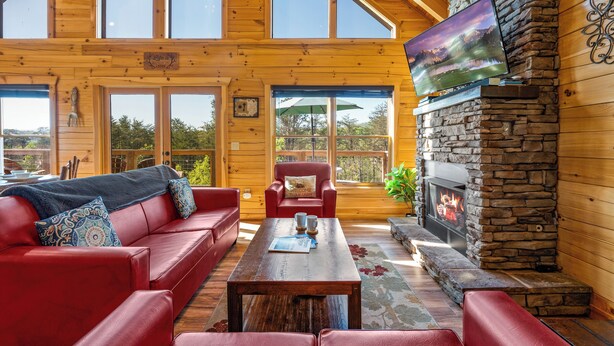 Un salón amplio con un sofá de cuero rojo, una mesa de centro de madera y una chimenea de piedra.