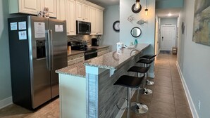 A modern kitchen with a central island, stainless steel appliances, and pendant lighting. - Wake Up to 1 Beautiful Vue - Beautiful Beachfront Condo! (Mexico Beach)