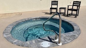 A hot tub with a metal ladder, surrounded by stone tiles, and two chairs. - Wake Up to 1 Beautiful Vue - Beautiful Beachfront Condo! (Mexico Beach)