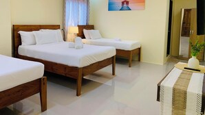 Habitación de hotel con dos camas de madera, un cuadro en la pared y una mesita con una planta.
