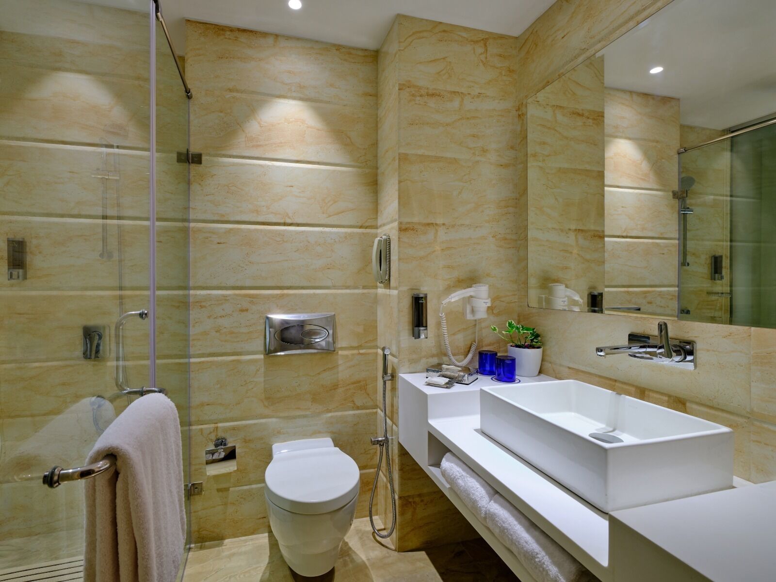 Une salle de bain moderne avec une douche à parois de verre, un lavabo blanc et un grand miroir.
