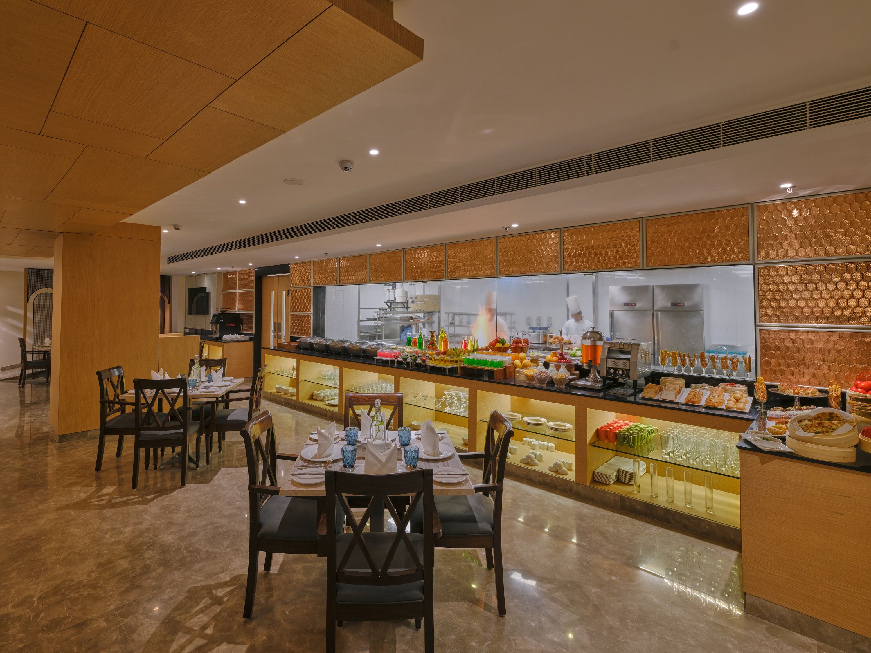 A modern restaurant with a long counter, multiple dining tables, and chairs.