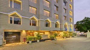 Um hotel com vários andares, fachada moderna, grandes janelas e área de entrada bem iluminada.