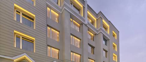 A multi-story hotel with a modern facade, large windows, and a well-lit entrance area.