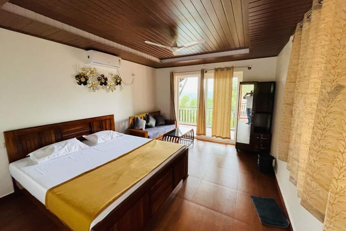 A bedroom with a wooden ceiling, a bed with a yellow blanket, a TV, and a balcony with curtains.