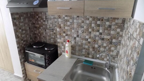 A compact kitchen with a microwave, a stove, and a sink. - VS studios Economy Double Room (Skiathos)