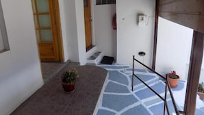A narrow hallway with a wooden door, a small step, and a potted plant. - VS studios Economy Double Room (Skiathos)