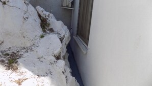A narrow snow-covered pathway leading to a building with a window and a door. - VS studios Economy Double Room (Skiathos)