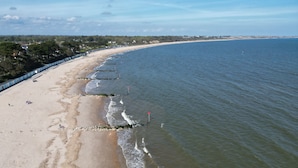A beach with a long stretch of sand, a few people, and a clear sky. - The Beach House - a stone's throw from Avon Beach, Friars Cliff (Christchurch)