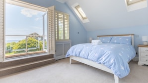 A bedroom with a bed, a window with shutters, a skylight, and a view of greenery outside. - The Beach House - a stone's throw from Avon Beach, Friars Cliff (Christchurch)