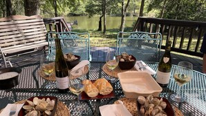 A table set with wine, bread, and clams, overlooking a lake. - This relaxing cabin is cozy and secluded with private pond and fishing dock (Kingston)