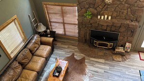 A cozy living room with a stone fireplace, leather sofa, and a TV. - This relaxing cabin is cozy and secluded with private pond and fishing dock (Kingston)