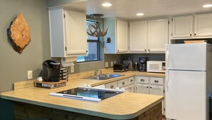 A modern kitchen with a central island, bar stools, white cabinets, and a built-in refrigerator. - This relaxing cabin is cozy and secluded with private pond and fishing dock (Kingston)